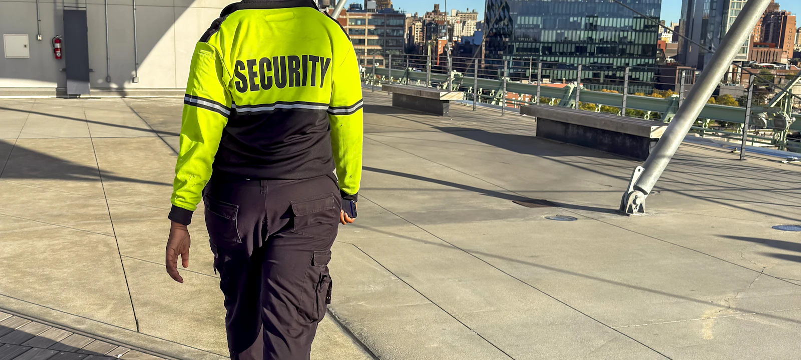Security guard in a high-visibility jacket overlooking a city skyline