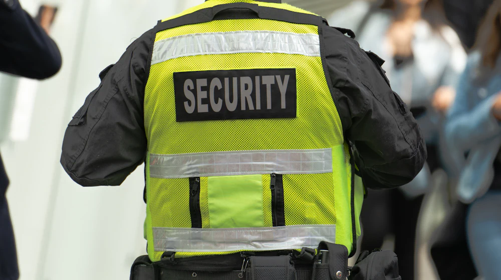Security guard in a high-visibility vest seen from behind in a public space
